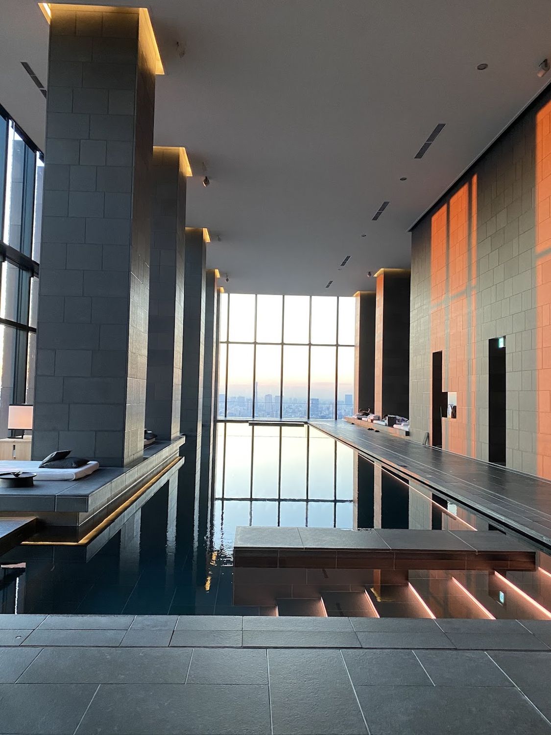 A long stone bathing pool beside tall windows in Tokyo