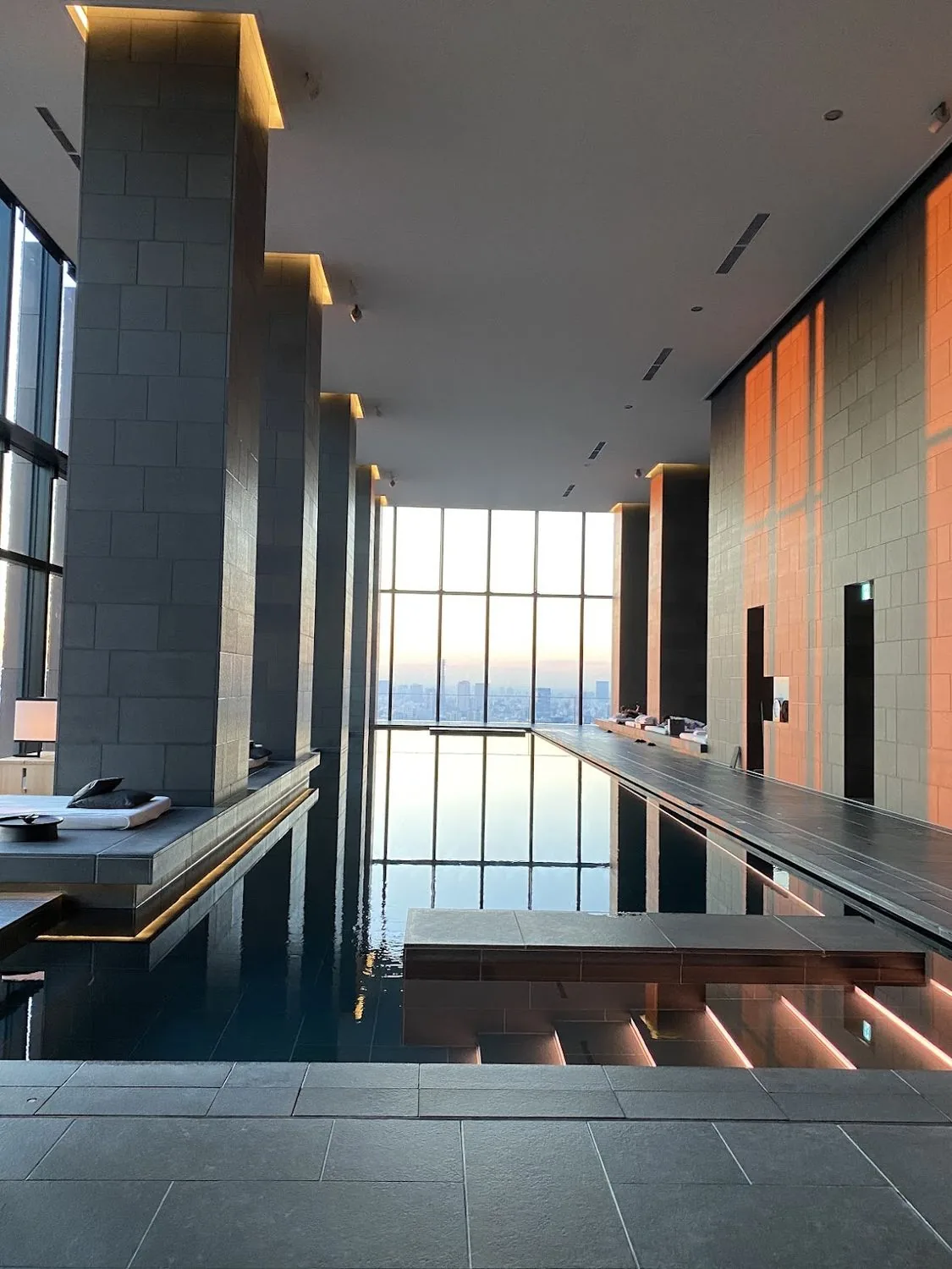 A stone bathing pool beside tall windows in Tokyo